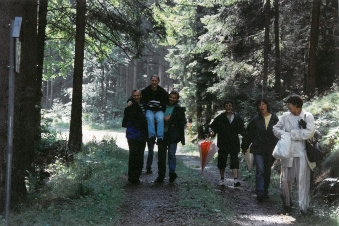 EIne Gruppe von Menschen heiter beim Wandern durch einen Wald